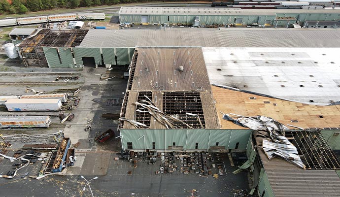 industrial building with significant roof damage from storm