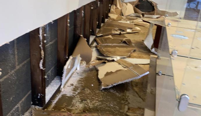 Damaged wall with exposed drywall and studs