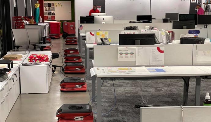 An office space with multiple air movers on the floor for drying purposes