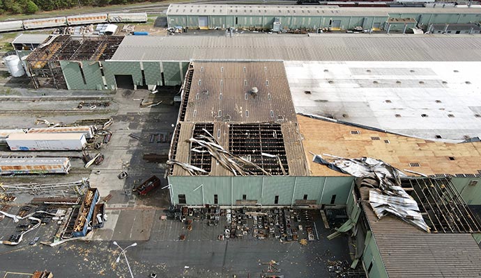 a storm damaged industrial building with a partially collapsed roof and scattered debris