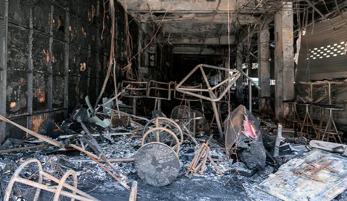 A charred room with burnt furniture and debris after a fire incident