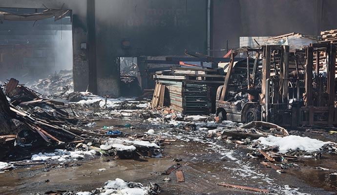 Charred warehouse with burnt debris and a damaged forklift