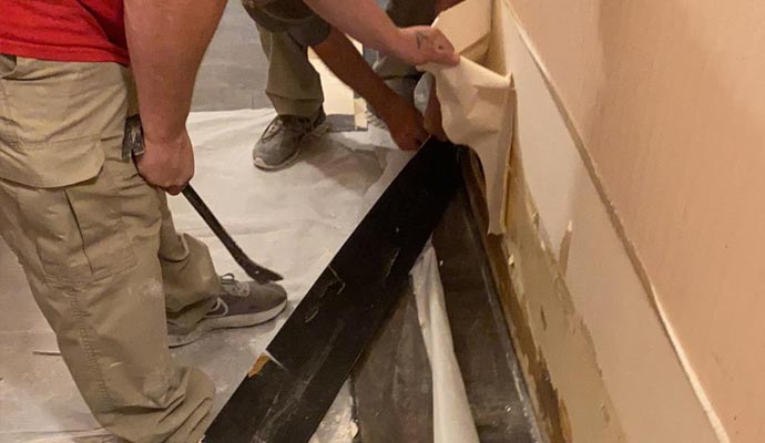 two people working on wall and floor repair