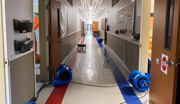 School hallway with floor fans for water damage restoration