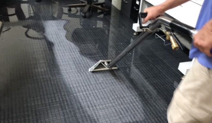 Person cleaning carpet with equipment