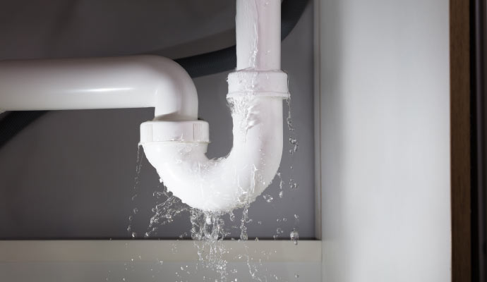 A leaking pipe joint under a sink